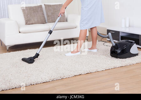 Bild der jungen Magd Reinigung Teppich mit Staubsauger zu Hause abgeschnitten Stockfoto