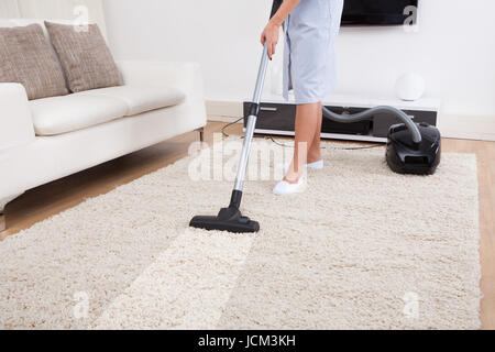 Bild der jungen Magd Reinigung Teppich mit Staubsauger zu Hause abgeschnitten Stockfoto