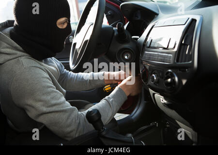 Seitenansicht der Dieb mit Schraubendreher im Auto Stockfoto