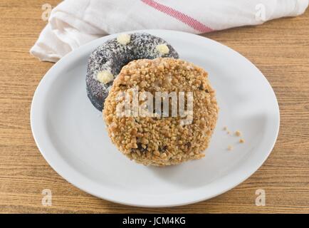 Lebensmittel und Bäckerei, Teller mit leckeren Schokoladen Donuts mit Sahnehäubchen und Erdnüsse Toppings. Stockfoto