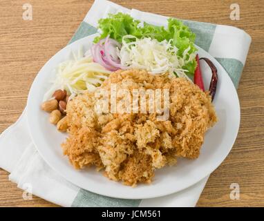 Thai-Küche und Essen, Thai traditionelle knusprig Wels Salat serviert mit grünen Eiche, geschreddert, grüne Mango, roten Zwiebeln, Kohl, Chili und Erdnuss. Stockfoto
