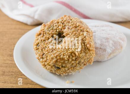 Lebensmittel und Bäckerei, Teller mit leckeren süßen Donuts mit Erdbeer-Marmelade, Schokolade und Erdnüssen Toppings Stockfoto