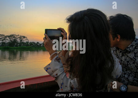 Eine Frau fotografiert von Zugvögeln, die mit ihrem Handy Arunima Resort am Panipara in Narail Bezirk. Bangladesch. Stockfoto