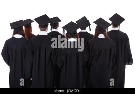 Große Gruppe von Absolventen stehen in den Kleidern und Quaste Hüte angesehen von hinten isoliert auf weiss Stockfoto