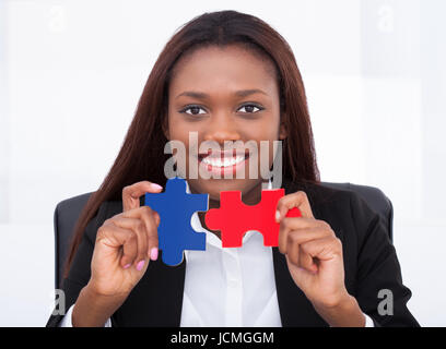 Porträt von zuversichtlich Geschäftsfrau hält Puzzleteile im Büro Stockfoto