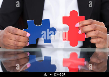 Porträt von zuversichtlich Geschäftsfrau hält Puzzleteile im Büro Stockfoto