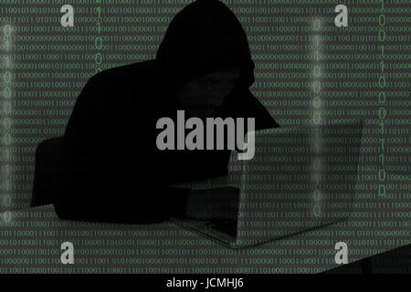 Computer-Hacker tragen ein Kapuzenshirt mit Laptop im Dunkeln. Der Mann bricht den Zugriff auf Daten zu stehlen und infizieren Computer und Systeme. Hackin Stockfoto