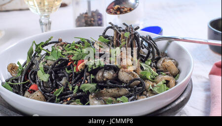 Beregnung kühlere Flocken über schwarze Pasta mit Tintenfisch (Sepia) und Tinte Stockfoto