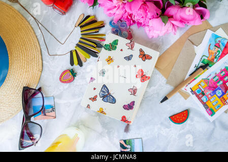 Urlaub planen Hintergrund. Notebook für Ideen und hellen Details: Hut, Sonnenbrille, Umschläge, Postkarten, Pfingstrosen, Limonade. Sommer-Konzept. Stockfoto