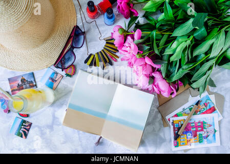 Urlaub planen Hintergrund. Notebook und hellen Details geöffnet: Hut, Sonnenbrille, Umschläge, Postkarten, Pfingstrosen, Limonade. Sommer-Konzept. An Stockfoto