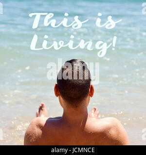 Closeup von einem kaukasischen Jüngling gesehen von hinten liegend Gesicht bis auf den Sand in das Meer und den Text, den das Leben ist Stockfoto