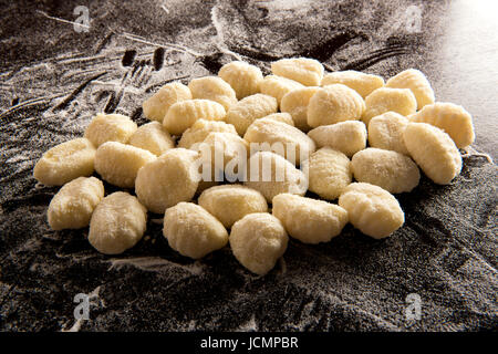 Haufen von handgemachte Gnocchi Nudeln Nahaufnahme auf bemehlten Garbehälter oder schwarzer Tischfläche Stockfoto