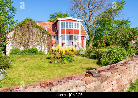 Ossby, Öland, Schweden - 28. Mai 2017: Umwelt-Dokumentarfilm. Schöne rote Haus und Garten in der kleinen Küstenstadt Dorf Ossby an einem sonnigen Tag. Stockfoto