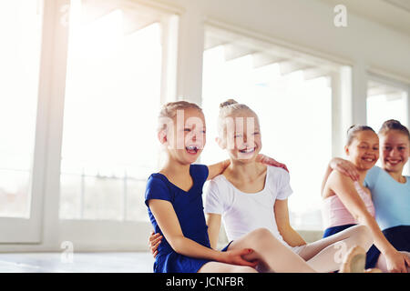 Niedliche kleine Mädchen umarmen und Lachen auf Boden in Ballett-Klasse zusammen sitzen. Stockfoto