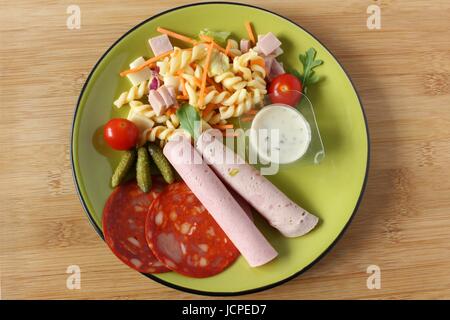 Ein Nudelsalat, Tomaten, Sauce und Wurst in einer Platte in Begleitung Stockfoto