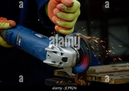 DIY mit einem Winkelschleifer. Nahaufnahme Manuelle Arbeit mit Funken fliegen. Exeter, Devon, Großbritannien. Juli 2015. Stockfoto