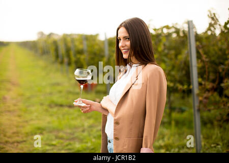 Hübsche junge Frau, die roten Weinprobe im Weinberg Stockfoto