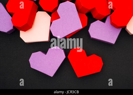 Rote und violette Origami-Herzen mit auf schwarzem Hintergrund Stockfoto