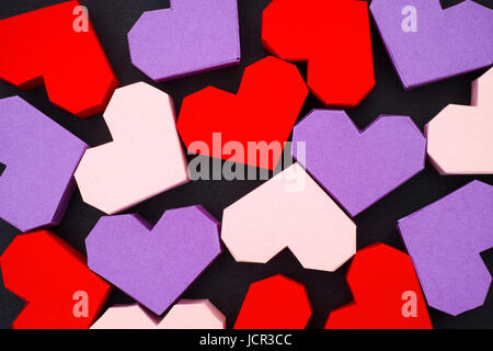 Rot, lila und rosa Origami-Herzen auf schwarzem Hintergrund Stockfoto