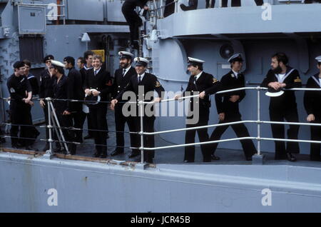 AJAXNETPHOTO. 19. JUNI. 1982. PORTSMOUTH, ENGLAND. -ÜBERLEBENDE RETURNS - CREW VON DER BOMBE BESCHÄDIGT TYP 42 (1 & 2) SHEFFIELD KLASSE ZERSTÖRER (3660 TONNEN) HMS GLASGOW IN JUBELNDER STIMMUNG ALS DAS SCHIFF KOMMT NACH HAUSE, EIN HERZLICHES WILLKOMMEN AUS FAHNENSCHWINGEN MASSEN VON GÖNNERN UND VERWANDTEN.  FOTO: JONATHAN EASTLAND/AJAX. REF: 21411 2 3 Stockfoto