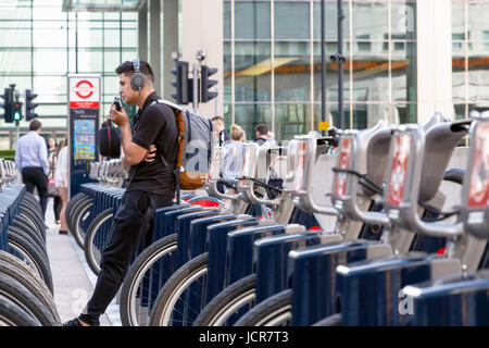 London, UK - 10. Mai 2017 - ein junger Mann stützte sich auf ein Santander Fahrrad an einer Docking-Station in Canary Wharf Stockfoto