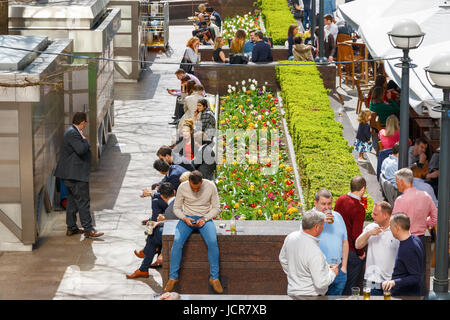 London, UK - 10. Mai 2017 - einen Platz im Freien in Canary Wharf voller Leute trinken und plaudern Geschäft an einem sonnigen Tag Stockfoto