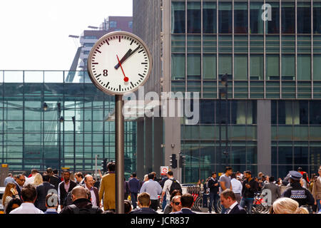 London, UK - 10. Mai 2017 - voller Leute, die zu Fuß durch eine öffentliche Uhr in Reuters Plaza, Canary Wharf Stockfoto