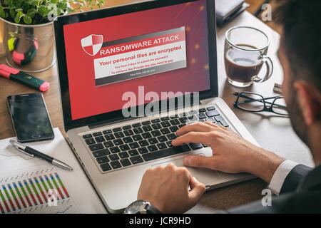 Ransomware Warnmeldung auf einem Laptop-Bildschirm - Mann bei der Arbeit Stockfoto