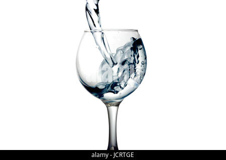 Farblose Flüssigkeit, Wasser wird Wodka in ein Glas Flüssigkeit in einem Lautsprecher, isoliert auf einem weißen Hintergrund gegossen. Stockfoto