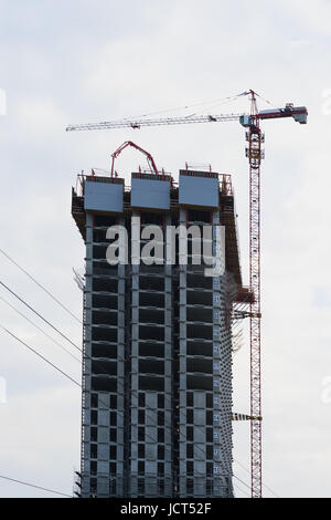 Baustelle des modernen Hochhaus. Aufzug-Turmdrehkran und neue Wohngebäude im Bau gegen blauen Himmel Stockfoto