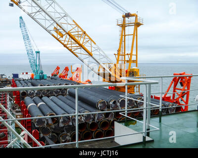 Das Deck legen Lastkahn. Rohre und heben Kräne auf dem Schiff. Ausrüstung für die Verlegung einer Pipeline auf dem Meeresboden. Stockfoto