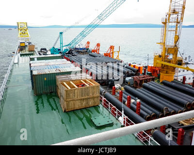 Das Deck legen Lastkahn. Rohre und heben Kräne auf dem Schiff. Ausrüstung für die Verlegung einer Pipeline auf dem Meeresboden. Stockfoto