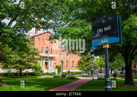 Friedrich, USA - 24. Mai 2017: Rathaus in der Innenstadt in Maryland mit Backsteinbau außen, Zeichen und Park-Platz mit Blumen und Polizist Stockfoto