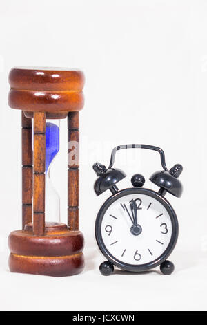 Schwarze Wecker und Sanduhr auf weißem Hintergrund Stockfoto