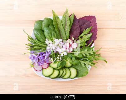 Salat mit verschiedenen Blättern, Gemüse und Blumen Stockfoto