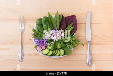 Salat mit verschiedenen Blättern, Gemüse und Blumen Stockfoto