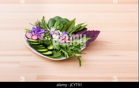 Salat mit verschiedenen Blättern, Gemüse und Blumen Stockfoto