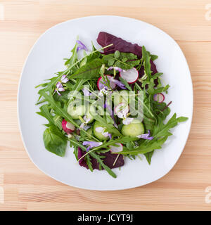 Salat mit verschiedenen Blättern, Gemüse und Blumen Stockfoto