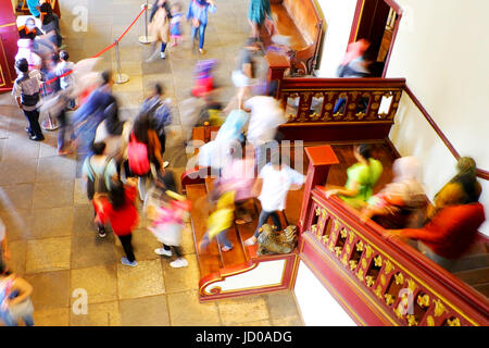 Touristen aus dem zweiten Stock hinunter in den ersten Stock durch die Holztreppe in einem historischen Gebäude in der Altstadt, Jakarta, Indonesien. Stockfoto