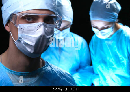 Drei Chirurgen bei der Arbeit im OP Theater sparen Patienten und Leben Monitor betrachten. Reanimationsteam Medizin Schutzmasken tragen. Stockfoto