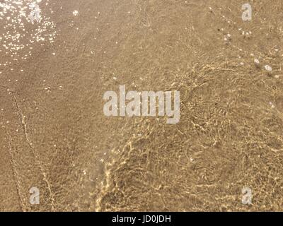 Frische gelbe Meeressand nach der Welle an der Küste. Stockfoto