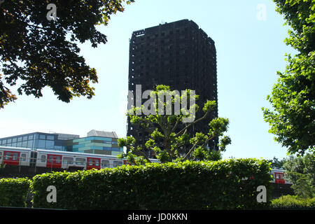 London, UK. 16. Juni 2017. Eine u-Bahn von Latimer Statin Geschwindigkeiten auf den Gleisen unter die verkohlten Überreste des Blocks 24-geschossiges Hochhaus Grenfell. Mindestens 30 Personen haben Bene tot mit etwa 70 fehlen und gefürchteten Toten bestätigt. Bildnachweis: David Mbiyu/Alamy Live-Nachrichten Stockfoto