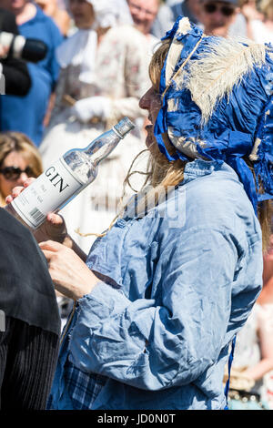 Ältere Frau, gekleidet in viktorianischen Kostüm, als Sarah Gamp, betrunkenen Charles Dickens Charakter, holding Flasche Gin und nahm einen Schluck aus der Flasche. Stockfoto
