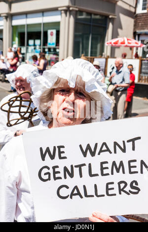 Ältere Dame verkleidet als viktorianische Küche Zimmermädchen holding Zeichen' wollen wir Herren der Anrufer. Nahaufnahme, Frau direkt auf Viewer beim Sprechen. Ein Teil der Parade während der broadstairs Dickens Woche Festival. Stockfoto