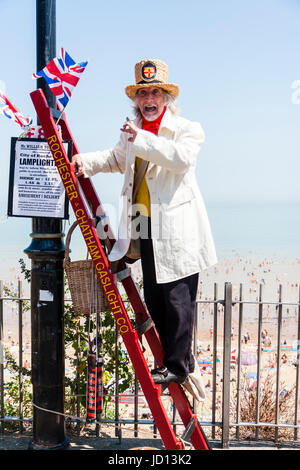 Herr William Thompkins, Anzünder, Charles Dickens Charakter, Geschichte. Das Tragen von weißen Mantel und Strohhut, steht auf Ladder gegen Licht mit Union Jack. Stockfoto