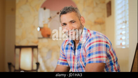 Porträt von homosexuellen Erwachsenen Mannes. Glücklich Hispanic Homosexuell lächelnd in die Kamera, sitzen auf dem Sofa zu Hause. Stockfoto