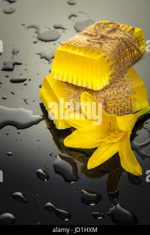 Handgemachte Seife auf einem schwarzen Hintergrund mit gelben Tropfen Wasser Stockfoto