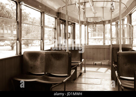 Innenraum einer alten Vintage Straßenbahn. Innen ist leer, hölzernen Sitze. Schatten. Durch die Fenster sehen Sie Bäume. Sepia. Melancholischen Hintergrund Stockfoto