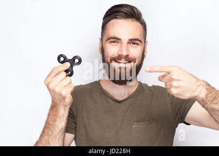 Junger Mann hält und spielt mit Fidget Spinner. Studio auf weißem Hintergrund gedreht. Stockfoto