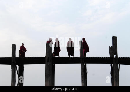 U-Bein Brücke/Amarapura - Myanmar 22. Januar 2016: Fünf buddhistische Mönche auf ihren täglichen Spaziergang über die weltweit längste Fußgängerbrücke kurz vor Sonnenaufgang. Stockfoto